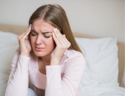 Young woman waking up with a morning headache - for sleep apnea info from Sugarland, TX dentist Siny Thomas, DMD