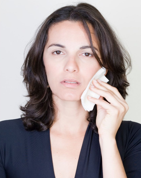 Brunette woman holding the side of her face portarying sweling after tooth extraction