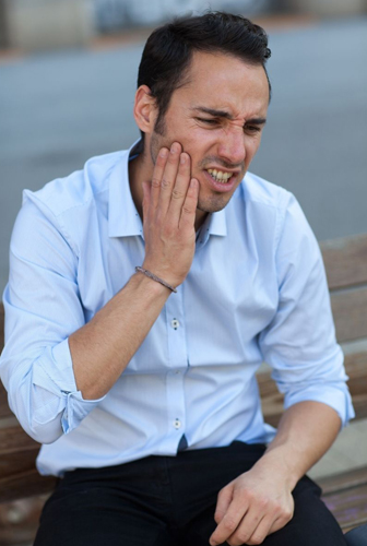 Man holding the side of his face, portraying a root canal dental emergency