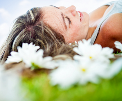 Woman lying in a field of daisies portraying the relaxing effects of dental sedation