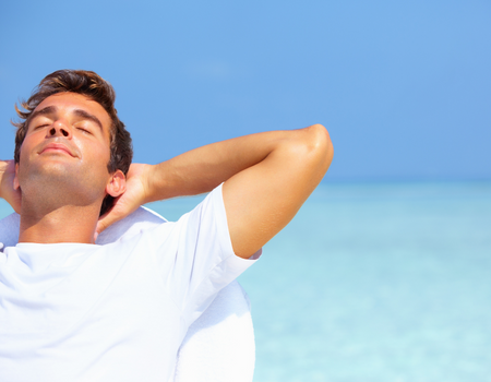Young man relaxing with his back to the ocean, portraying the relaxation of sedation dentistry, available from Sugar Land dentist Dr. Siny Thomas