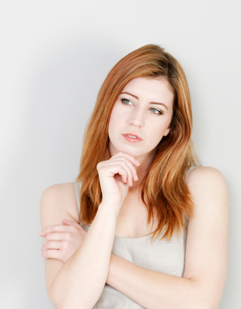 Red-haired woman thinking, portraying concern about holistic dentistry and autoimmune disease