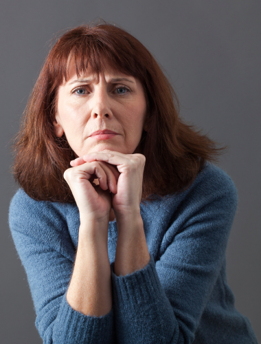 Red-hed mature woman portraying disappointment over dental bridge with a too-long tooth